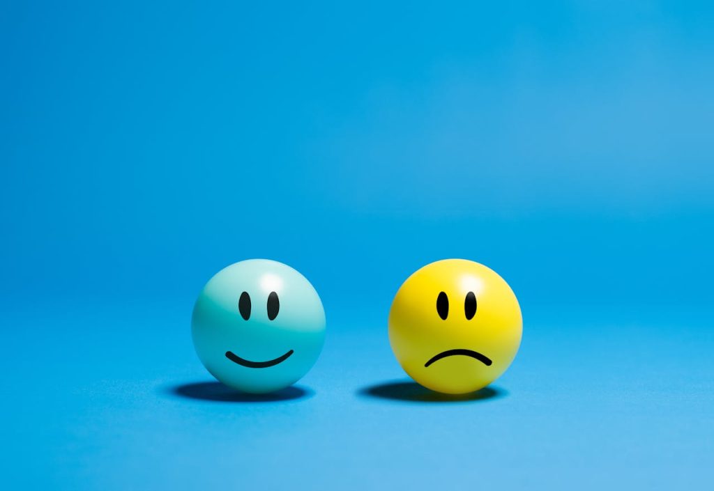 pexels photo 29205873 Two smiley balls representing opposite emotions on a blue background.