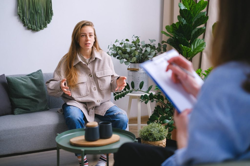 pexels photo 7176029 A woman engages in a therapy session, discussing issues with a counselor inside a modern office.